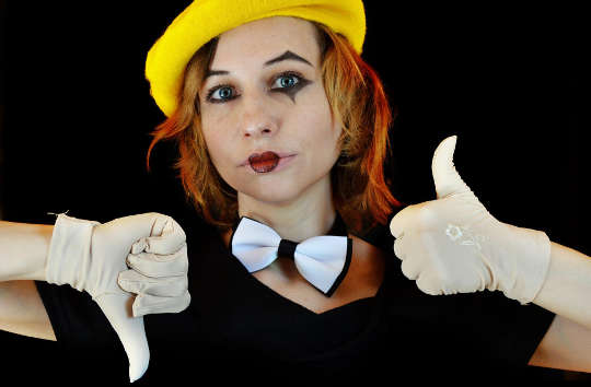 The Work Experience from Boomer Management to Gen X a young woman wearing a bow tie and a clown face with white gloves giving a thumbs up and thumbs down